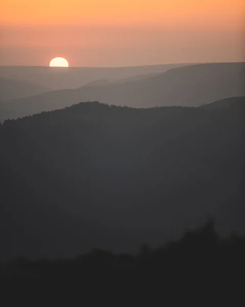 丘の列のシルエットの後ろにオレンジ色の夕日の素晴らしい背景 — ストック写真