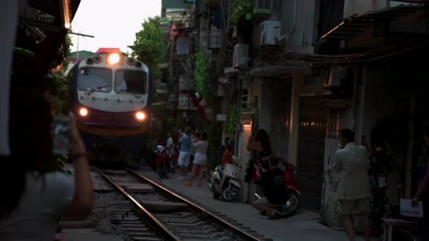 Hanói, Vietnã - 18 de outubro de 2019: Turistas ficam em frente a um trem se aproximando na Train Street em Hanói — Vídeo de Stock