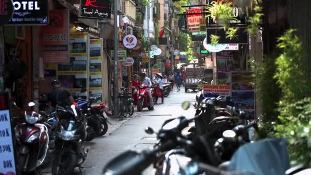 Hanoi, Vietnam - 10 Ekim 2019: İnsanlar scooterların ve motosikletlerin yanında dar sokaklarda yürüyor — Stok video