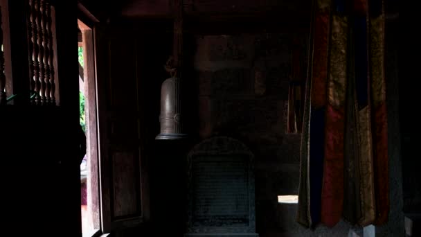 Dark room in Bich Dong Pagoda in Vietnam with religious items and a metal bell in the room — Stock Video