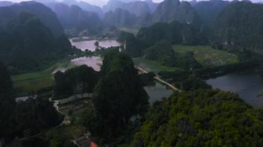 Tam Coc 'un Kuzey Vietnam' daki Ninh Binh eyaletinde günbatımında tam Coc ve pirinç tarlalarının 4k hava görüntüleri.