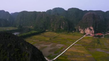 Tam Coc 'un Kuzey Vietnam' daki Ninh Binh eyaletinde günbatımında tam Coc ve pirinç tarlalarının 4k hava görüntüleri.