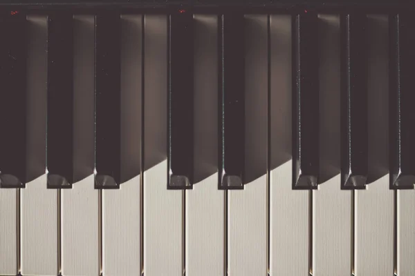 El primer plano de las teclas marfil blanco y negro en el piano de arriba con las sombras — Foto de Stock