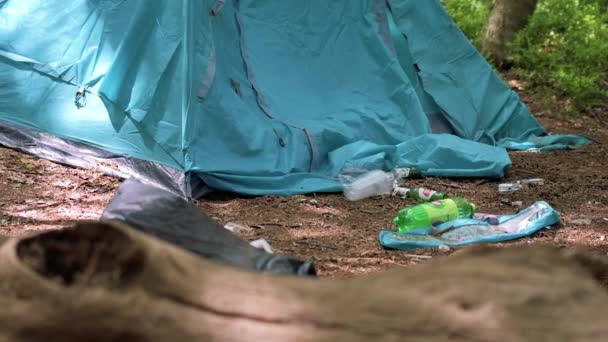 Slow motion beelden van bier en plastic flessen achtergelaten naast verlaten tent op een camping — Stockvideo