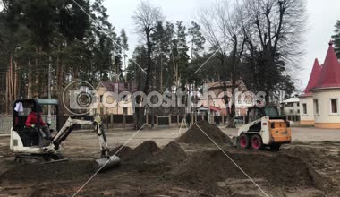 Operasyonda iki Traktörler. Tarak yere kazıyor. İşçi ağır makine üzerinde çalışıyorum. İnşaatçılar kaldırım döşeme döşenmesi için toprak seviye.