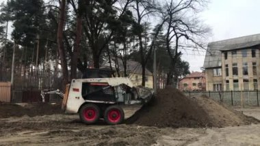 Operasyonda iki Traktörler. Tarak yere kazıyor. İşçi ağır makine üzerinde çalışıyorum. İnşaatçılar kaldırım döşeme döşenmesi için toprak seviye.
