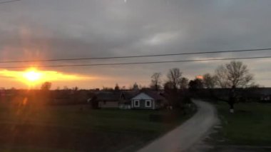 Yüksek hızlı trenin penceresinden doğanın arka planında gün batımı. Güneş, gökyüzü ve ağaçlar tren penceresinden görülebilir..