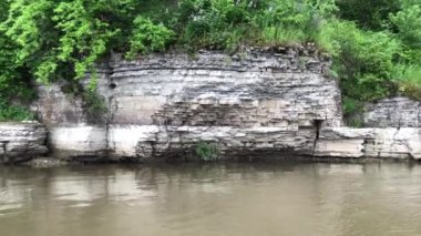 Dinyester Nehri'nin kanyonu boyunca bir katamaran üzerinde rafting. Taşlı, yeşil kıyı sudan yansıyan.