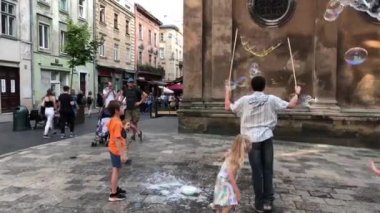 Bir adam sabun köpüğü yapar, etrafında farklı çocuklar toplanır. Eski bir Avrupa şehrinin sokağında, çocuklar sabun kabarcıkları görünce sevinirler. Lviv, şehir merkezi, 8 Haziran 2019