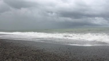 Denizde fırtına, sahilde fırtına uyarısı. Fırtına sırasında gök gürültülü bulutlar ve büyük deniz dalgaları. Gürcistan'da Karadeniz'de büyük fırtına dalgaları karaya vurdu.