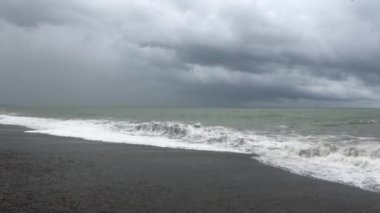 Denizde fırtına, sahilde fırtına uyarısı. Fırtına sırasında gök gürültülü bulutlar ve büyük deniz dalgaları. Gürcistan'da Karadeniz'de büyük fırtına dalgaları karaya vurdu.