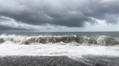 Denizde fırtına, sahilde fırtına uyarısı. Fırtına sırasında gök gürültülü bulutlar ve büyük deniz dalgaları. Gürcistan'da Karadeniz'de büyük fırtına dalgaları karaya vurdu.