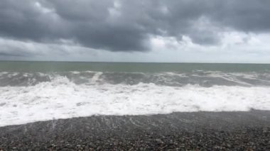 Denizde fırtına, sahilde fırtına uyarısı. Fırtına sırasında gök gürültülü bulutlar ve büyük deniz dalgaları. Gürcistan'da Karadeniz'de büyük fırtına dalgaları karaya vurdu.