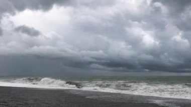 Denizde fırtına, sahilde fırtına uyarısı. Fırtına sırasında gök gürültülü bulutlar ve büyük deniz dalgaları. Gürcistan'da Karadeniz'de büyük fırtına dalgaları karaya vurdu.