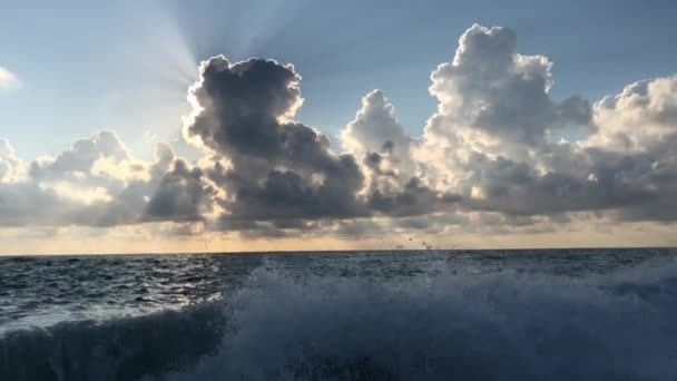 ビーチからの眺め 海の美しい夕日 太陽の光が雲を貫通する 海の夏の夕方 雲と青い空 太陽が水に反射され 波が海岸に打ち寄せる — ストック動画