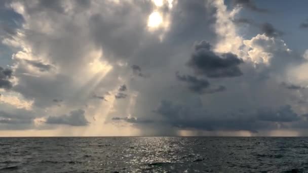 ビーチからの眺め 海の美しい夕日 太陽の光が雲を貫通する 海の夏の夕方 雲と青い空 太陽が水に反射され 波が海岸に打ち寄せる — ストック動画