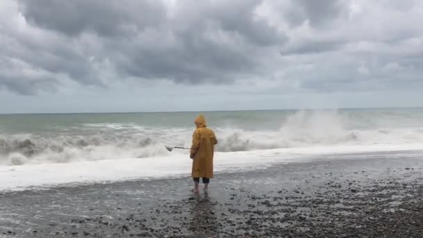 暴风雨时在海滩上用金属探测器的人一个男人正在海滩上寻找珠宝 风暴云和大海浪在风暴警报在海岸 — 图库视频影像