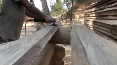 Bir işçi bir taşlama aleti ile bir çam tahtası parlatır. Adam elinde taşlama ve ahşap bir tahta nın yüzeyi parlatma için bir güç aracıdır. Bir ahşap ustası kendi elleriyle çalışır..