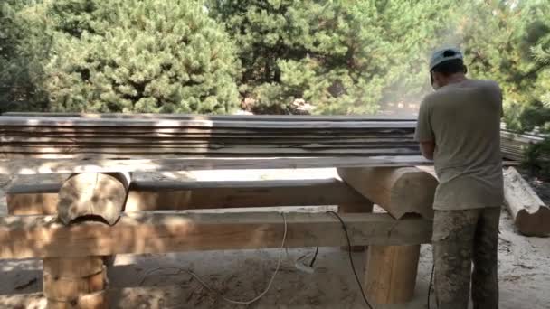 労働者は研削工具で松板を磨く 人間の手の中で 木製のボードの表面を研削し 研磨するための電動工具です 木工職人は自分の手で働く — ストック動画