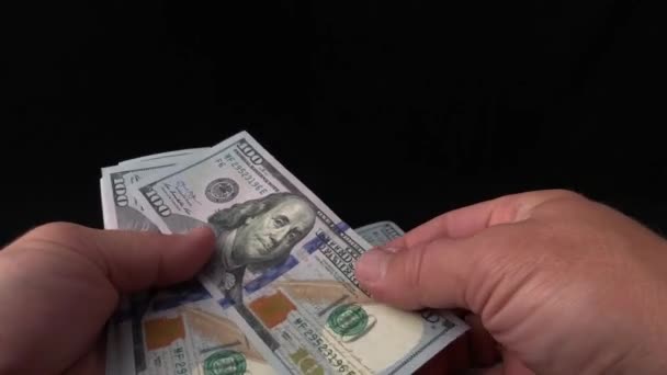 男は黒い背景でドルを数える 男の手にアメリカのお金の束 100ドル札を偽物で調べてるコンセプト 豊かさ 偽のお金の検証 — ストック動画