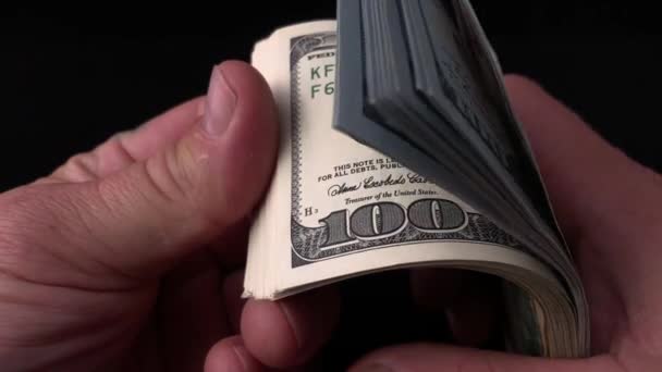 男は黒い背景でドルを数える 男の手にアメリカのお金の束 100ドル札を偽物で調べてるコンセプト 豊かさ 偽のお金の検証 — ストック動画