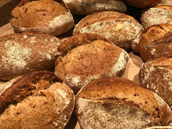 Bir sürü pişmiş yuvarlak ekmek. Rafta taze buğday ekmeği. Arka plan dokusu: günlük ekmek. — Stok fotoğraf