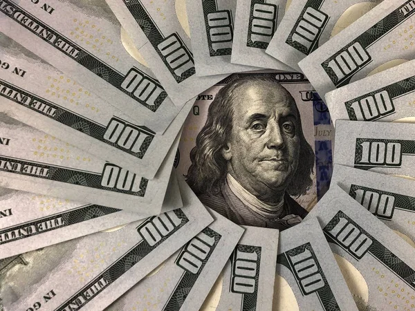 100 Amerikan dolarının banknotları bir çemberin içinde. Benjamin Franklin 'in görüntüsü yüz dolarlık banknotlarla çevrilidir. Masadaki Amerikan parası..