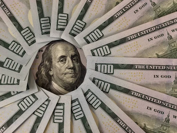 100 Amerikan dolarının banknotları bir çemberin içinde. Benjamin Franklin 'in görüntüsü yüz dolarlık banknotlarla çevrilidir. Masadaki Amerikan parası..
