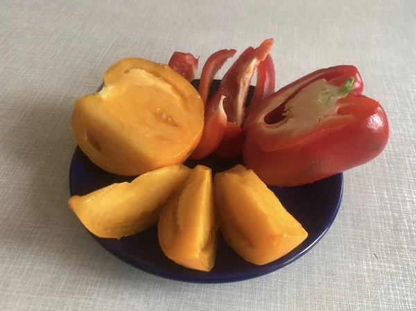 In a saucer yellow tomato and red pepper. Half a tomato and chopped bell pepper. — Stok fotoğraf