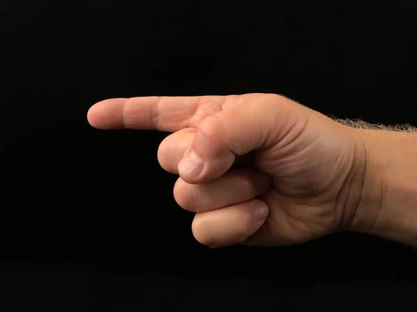 Signo de mano, el dedo índice apunta hacia un lado, sobre un fondo negro. Gesto con un dedo, la dirección del camino . — Foto de Stock