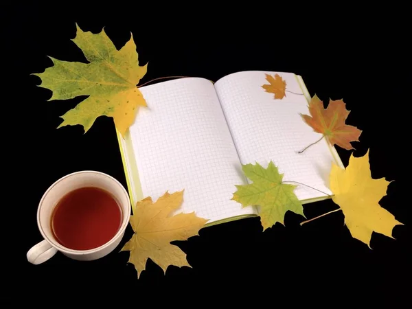 Musim gugur masih hidup di atas meja gelap. Cangkir kopi, buku catatan dan daun di latar belakang hitam. Buka buku, daun kuning, tampilan atas . — Stok Foto