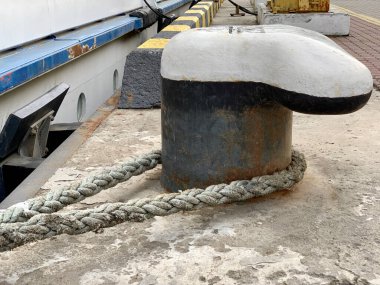 Geminin ipi rıhtımdaki bir direğe bağlı. Gemi kıyıya demir attı. Kalın bir ip tekneyi iskelede tutuyor. Kavram: Güç, güç, bağlantı