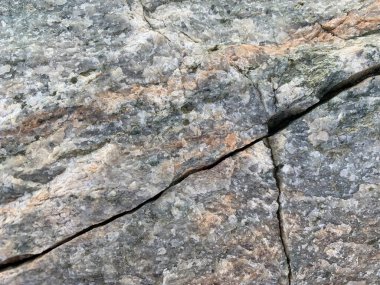 Arkaplan dokusu: büyük bir taşın yapısı. Granit kaya, yakın çekim. Taş kayalarda düzensizlikler ve çatlaklar var. Kavram - taş, sertlik, güç