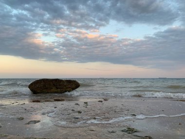 Arkaplan dokusu: Denizde büyük bir taş. Düşen taşın bir parçası deniz ve gökyüzünün arka planına karşı. Kavram - taş, sertlik, sağlam temel