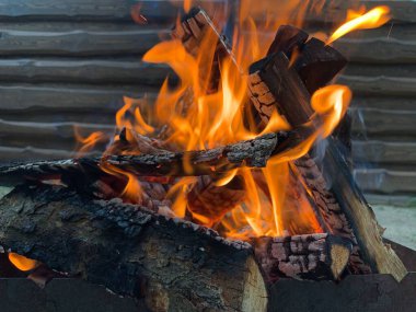 Izgarada ateş yanıyor, yakın plan. Kesilmiş odundan çıkan ateş alevi. Bahçede ateşin kırmızı dilleri var. Kavram: sıcaklık, ateş, yüksek sıcaklık