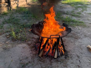 Izgarada ateş yanıyor, yakın plan. Kesilmiş odundan çıkan ateş alevi. Bahçede ateşin kırmızı dilleri var. Kavram: sıcaklık, ateş, yüksek sıcaklık