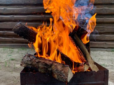 Izgarada ateş yanıyor, yakın plan. Kesilmiş odundan çıkan ateş alevi. Bahçede ateşin kırmızı dilleri var. Kavram: sıcaklık, ateş, yüksek sıcaklık