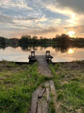 Ormandaki bir gölde akşam manzarası. Orman göletinde gün batımı. Nehirdeki balıkçılık platformu.