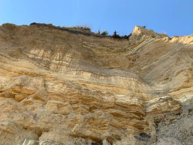 Denizin kıyısındaki dağın dik yamacında. Okyanus kıyısındaki kum dağı. Deniz tepesi kıyıya yakın.