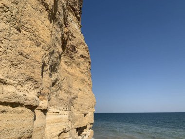 Denizin kıyısındaki dağın dik yamacında. Okyanus kıyısındaki kum dağı. Deniz tepesi kıyıya yakın.
