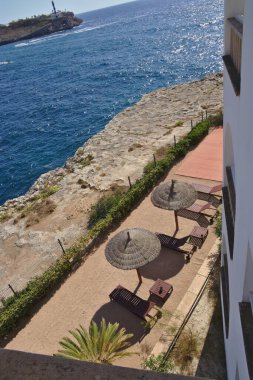 Kayalık kıyı şeridinin yanında güneş şemsiyeleri olan dinlenme yerleri