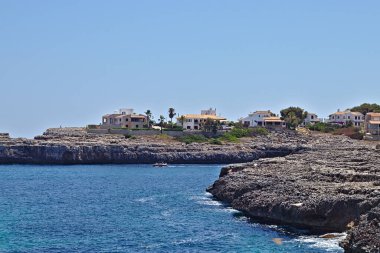 Mavi gökyüzü ve arkada evleri olan Rocky Coastline.