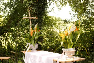 Dışarıda ağaçlarla çevrili bir düğün için dekore edilmiş sunak düzenlemesi.