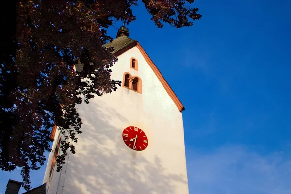 Wieża Czerwonym Zegarem Otoczona Drzewami Niebieskim Niebem — Zdjęcie stockowe