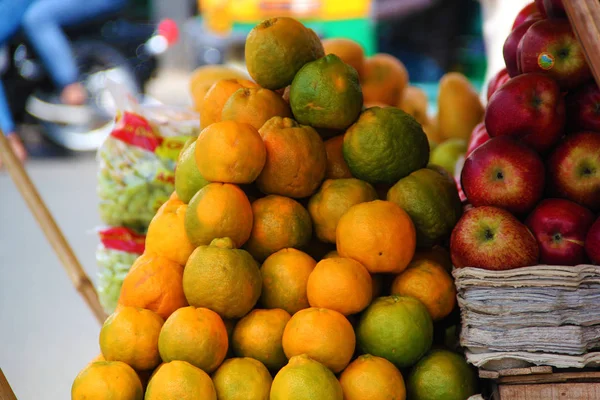 A bunch of ripe orange oranges and Red Apples on the counter in a street shop in India.