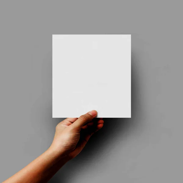 Hand hält leeres Papierblatt Format A5 auf grauem Hintergrund. — Stockfoto