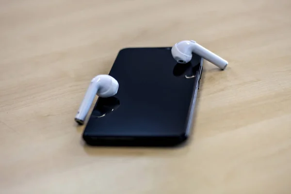 Smartphone com fones de ouvido no fundo de madeira — Fotografia de Stock