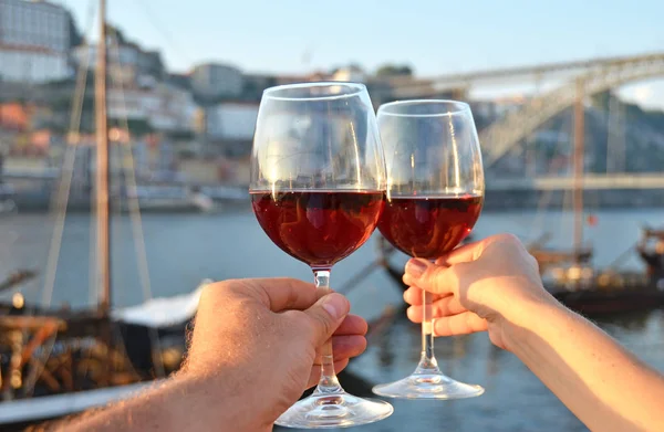 Wine glasses in the hands against Douro river in Porto, Portugal
