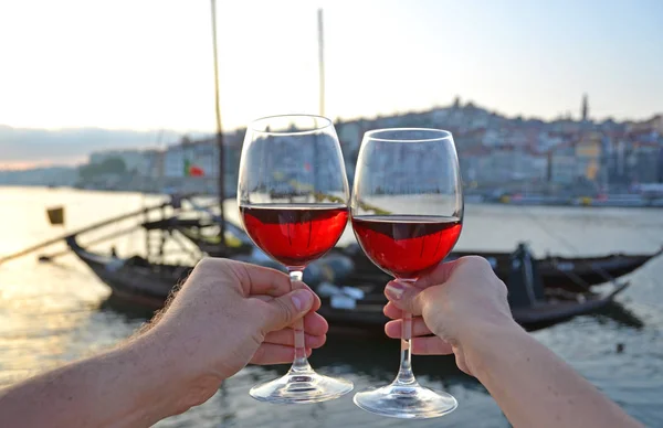 Wine glasses in the hands against Douro river in Porto, Portugal