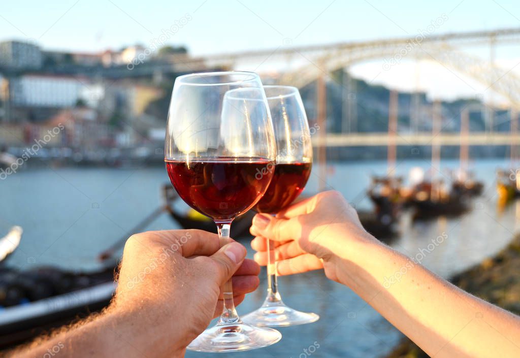 Wine glasses in the hands against Douro river in Porto, Portugal